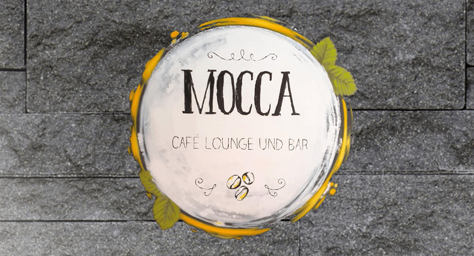 Ein weißer Kreis mit Schriftzug "Mocca - Café Lounge und Bar" auf einem steinernden Boden.