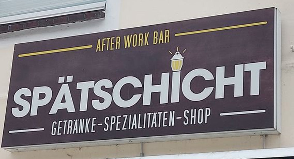 Logo des Shops "Spätschicht" an einer Hauswand mit Info "After Work Bar", "Getränke-Spezialitäten-Shop".