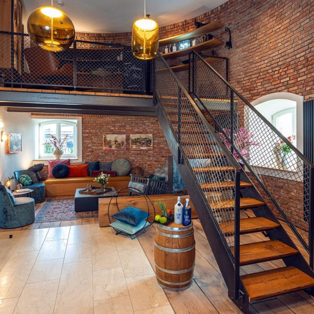 Einblick in das Hotelzimmer vom Wasserturm Bad Segeberg mit Sitzecke und hölzerner Treppe.