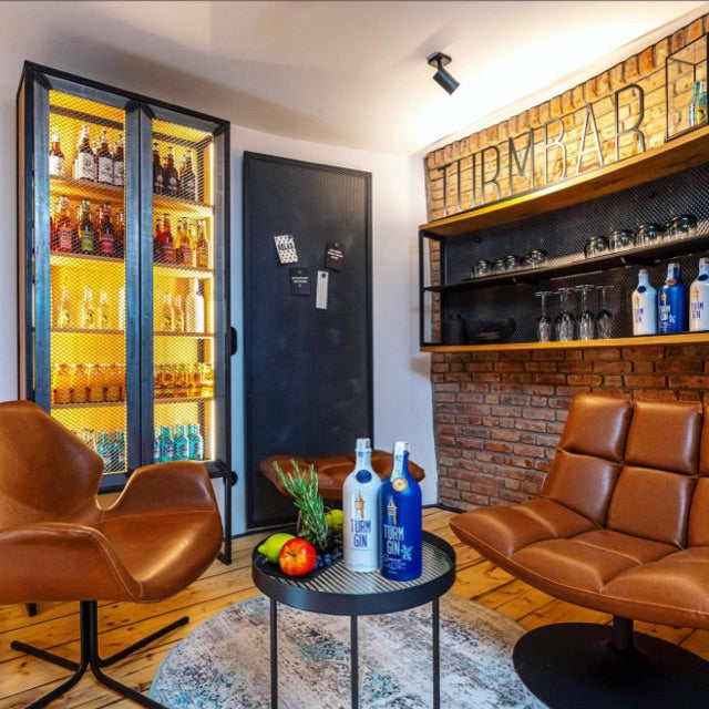 Blick in die TURM BAR im Wasserturm Bad Segeberg mit gemütlicher Sitzecke und Gin-Kühlschrank.