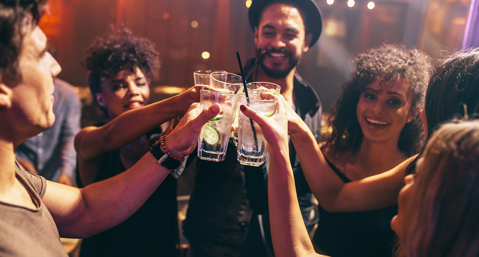 Eine Gruppe Menschen stößt beim Feiern mit Gin Cocktails in einem Club an.