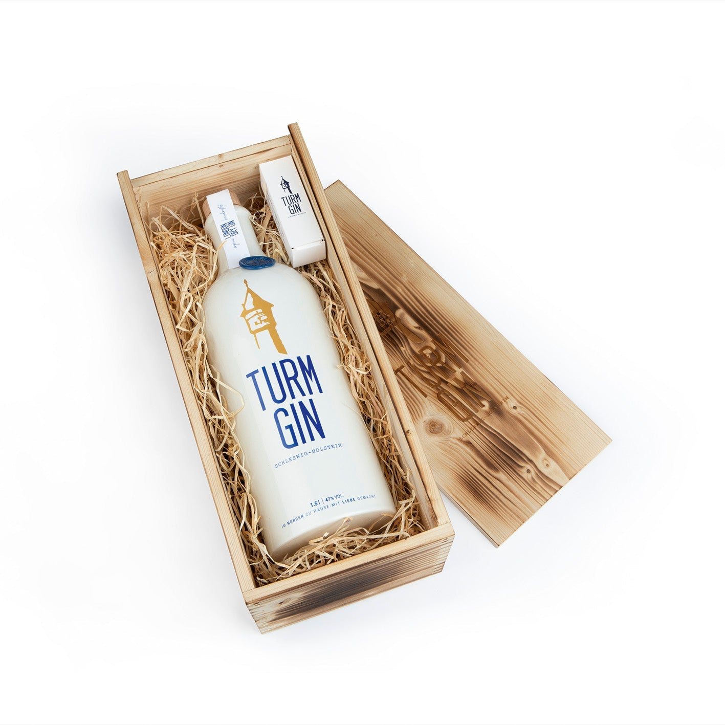 TURM GIN Magnum-Flasche mit 1,5 Litern verpackt in Holzverpackung auf Stroh vor weißem Hintergrund.